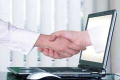 La página web del despacho: algo más que recordar la dirección y el teléfono De la pantalla de un portatil sale una mano y le da la mano a otra persona