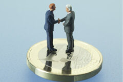 ¿Por qué los abogados tenemos que negociar con los clientes? Muñecos de dos personas estrechándose las manos sobre una moneda de un euro