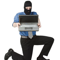 Hombre con un pasamontañas sujetando un ordenador portatil