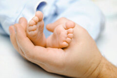 ¿El padre tiene derecho a disfrutar del permiso por lactancia, a pesar de que la madre no trabaje? Mano de un padre cogiendo los pies de un bebé