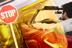 Conductor borracho: reducción de la indemnización al ocupante lesionado que lo sabía Un conductor delante de la señal de stop y un jarra de cerveza difuminadad