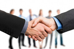 Los Tribunales rechazan el decaimiento de los convenios: también en convenios colectivos “sin pacto en contrario” Dos manos estrechándose con personas de fondo