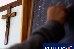 Los crucifijos en clase Un crucifijo en la pared y un estudiante escribiendo en la pizarra