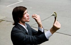 La condena en costas a la Administración, ¿un brindis al sol? Un ejecutivo joven mirando un taco de billetes con adoración.