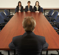 Un jefe en el lado de una larga mesa y tres trabajadoras en elotro extremo
