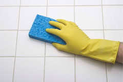 Maltrata a la empleada de hogar Mano con guante amarillo limpiando