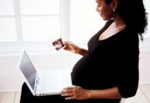 ¿Tiene prioridad de permanencia o de recolocación la trabajadora embarazada en un Despido Colectivo? Una mujer embarazada sentada con un portátil.