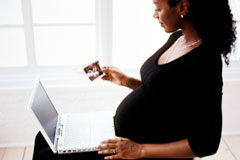 ¿Tiene prioridad de permanencia o de recolocación la trabajadora embarazada en un Despido Colectivo? Una mujer embarazada sentada con un portátil.