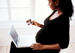 Una mujer embarazada sentada con un portátil.