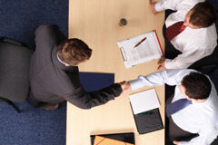 Seguro múltiple ¿puede haber diversos tomadores? Dos personas detrás de una mesa y otra delante dándoles la mano