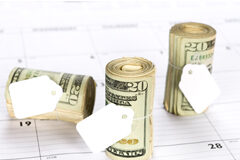 Nuevo modelo para efectuar los pagos fraccionados a cuenta del Impuesto sobre Sociedades en régimen de consolidación fiscal Un calendario y sobre él tres tacos de dinero cada uno de ellos con una etiqueta en blanco