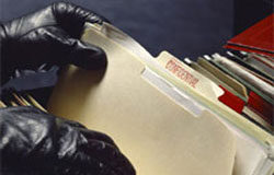 A vueltas con SITEL: ¿una brecha en el muro? Manos con guantes separando archivos