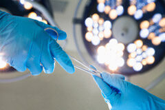 EL IVA ingresa en el quirófano Unas manos enguantadas pasándose unas tijeras quirúrgicas