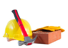 Un casco amarillo, guantes, un martillo y un ladrillo. Un casco amarillo, guantes, un martillo y un ladrillo.