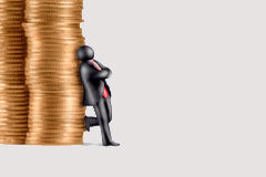 Salarios y productividad Un muñequito apoyado en una torre de monedas.