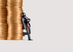 Un muñequito apoyado en una torre de monedas.