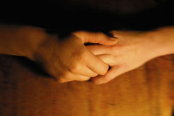 Dos manos entrelazadas sobre un fondo marrón.
