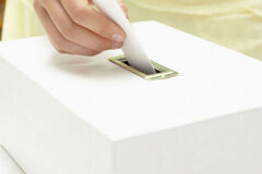 ¿Cómo computan los votos emitidos en blanco a efectos del cálculo del porcentaje determinante para la obtención del número de representantes? Mano metiendo voto en una urna