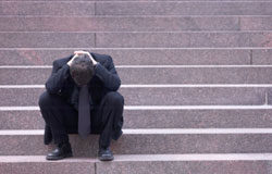 Miedos y falsas creencias profesionales en el sector jurídico Un abogado sentado en unas escaleras pensando en su futuro.