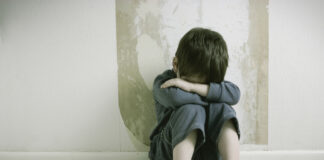 ¿Está relacionado el acoso escolar con el acoso laboral? Un niño sentado tapándose la cara.