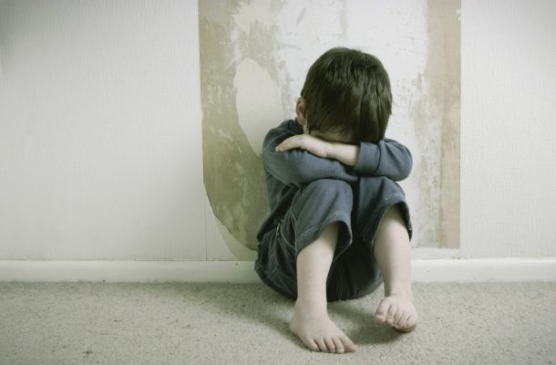 Un niño sentado tapándose la cara. Un niño sentado tapándose la cara.