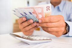 La retribución del administrador en el Impuesto sobre Sociedades Una persona con billetes en la mano y una calculadora