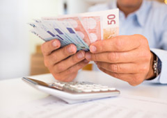 Una persona con billetes en la mano y una calculadora Una persona con billetes en la mano y una calculadora