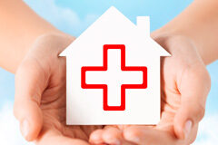 Cuota de asilo en la UE, presente y futuro inmediato Cogidos por unas manos casa de papel blanco con el signo de la cruz roja