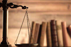Penas, procesos y órganos judiciales Una balanza de justicia con unos libros al fondo