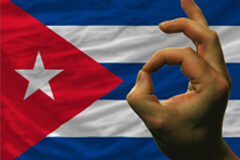 La compraventa de acciones de empresa mixta cubana por inversor extranjero Bandera cubana con un mano delante haciendo ok