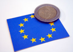 Una moneda de euro encima de una bandera de la UE