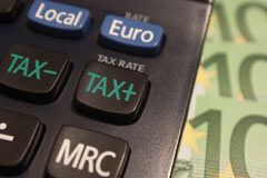 ¿Qué importe tributa de la indemnización abonada por despido al deportista profesional? Unos billetes de 50 euros al lado de una calculadora donde en una de las teclas pone TAX más y en otra TAX menos