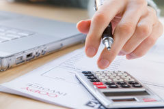 Medidas ilegales para el cobro de cuotas comunitarias Una persona haciendo cálculos en la calculadora y el ordenador