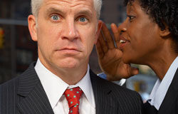 Revelación de secretos ¿Delito o competencia desleal? Mujer diciéndole al oído un chisme a un hombre