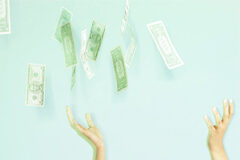 Miembros del consejo de administración desviaban dinero para su propio beneficio Fajos de billetes cayendo mientras unas manos intentan cogerlo.