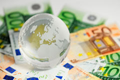 Nueva regulación de la modificación de los contratos del sector público en la Ley de Economía Sostenible Una bola del mundo sobre billetes de euro.