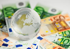 Una bola del mundo sobre billetes de euro.