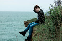 Emancipación del menor: 5 claves para entender lo que significa para los padres Un menor sentado en un acantilado