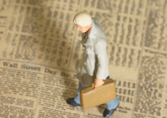 Figura de hombre con maletín andando encima de un periódico