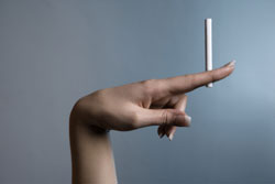 Una mano mostrando un cigarro encendido.