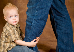 Un hijo sentado encima del pie del padre y agarrándole la pierna