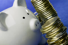 Última oportunidad para ahorrar impuestos Una hucha de un cerdito blanco y al lado unas monedas apiladas