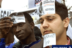 Actuación policial ante la estancia irregular en España según reciente circular emitida por la Dirección General de la Policía 2 extranjeros manifestándose y con pegatinas en la cara en contra de la Ley de Extranjería