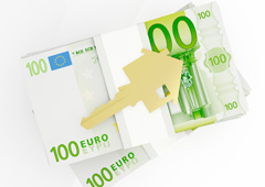 Una llave con forma de casa sobre billetes de 100 euros