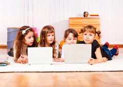 Cuatro niñas delante de dos ordenadores portátiles