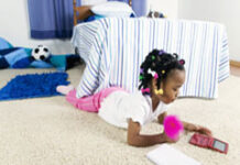 La dispensa de testificar en el caso de los menores de edad Una niña echada en el suelo jugando con la nintendo.