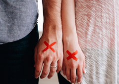 Una pareja con una x roja pintada en la mano