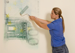 Una mujer pintando con un rodillo un billete de 1000 euros en la pared