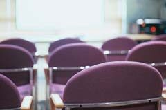 Sobre la competencia de la junta general en las «sociedades de capital» Sala con sillas vacías y una pantalla en la pared