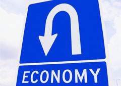 Una señal de curva peligrosa y debajo el letrero con la palabra 'economy'